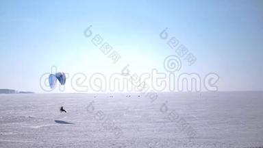 PA滑翔伞在地平线上结冰的湖面上滑行. 高清1080便士